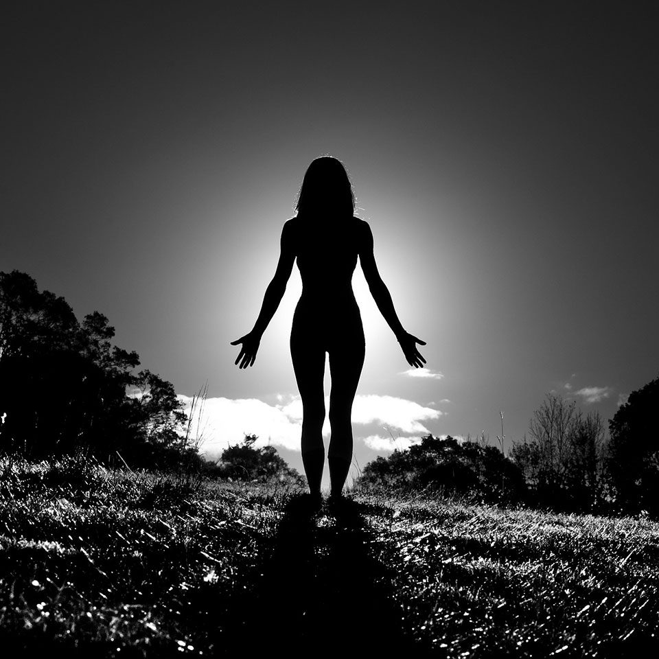 Female silhouette, outside in mountain pose.