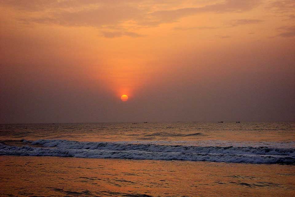 A red sun rises over the surf at dawn