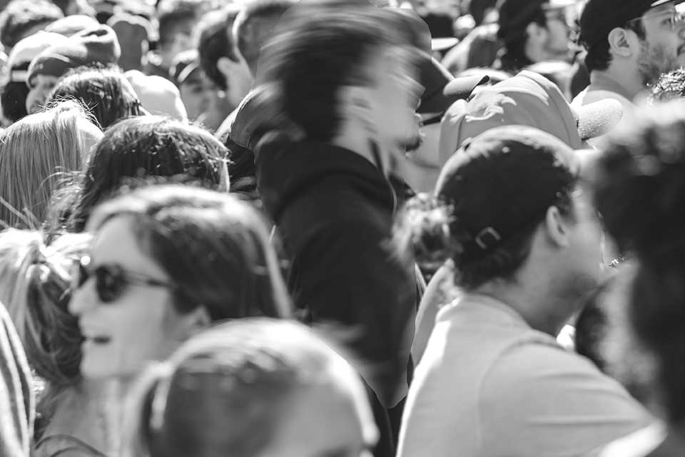 A black and white photo of a crowd with a figure at its center who is blurred