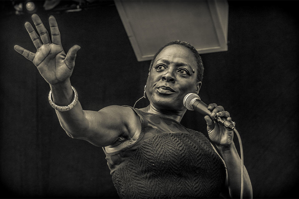 A photograph of Sharon Jones singing