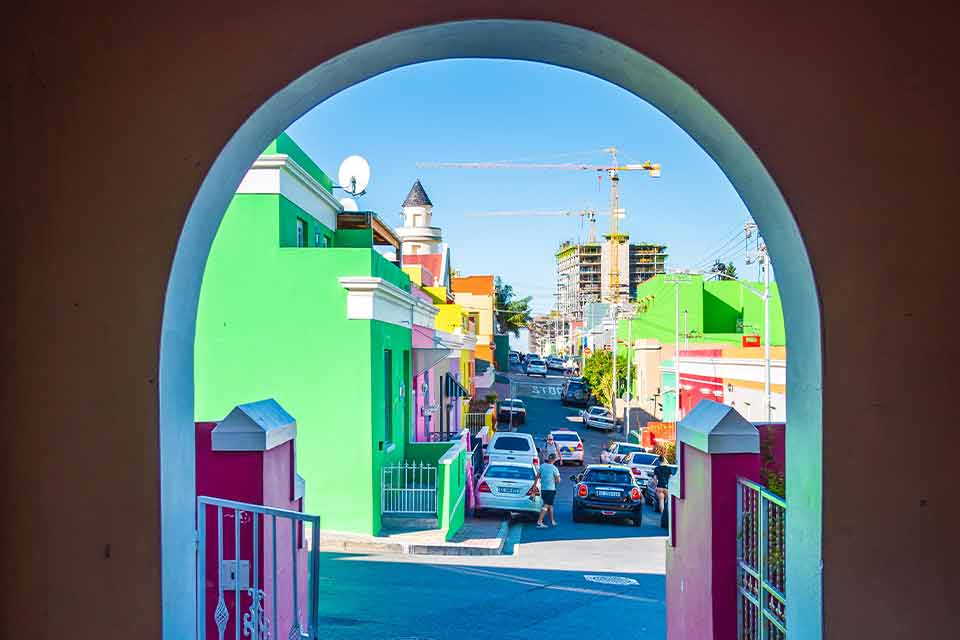 A photograph looking down a colorful city street through a painted archway