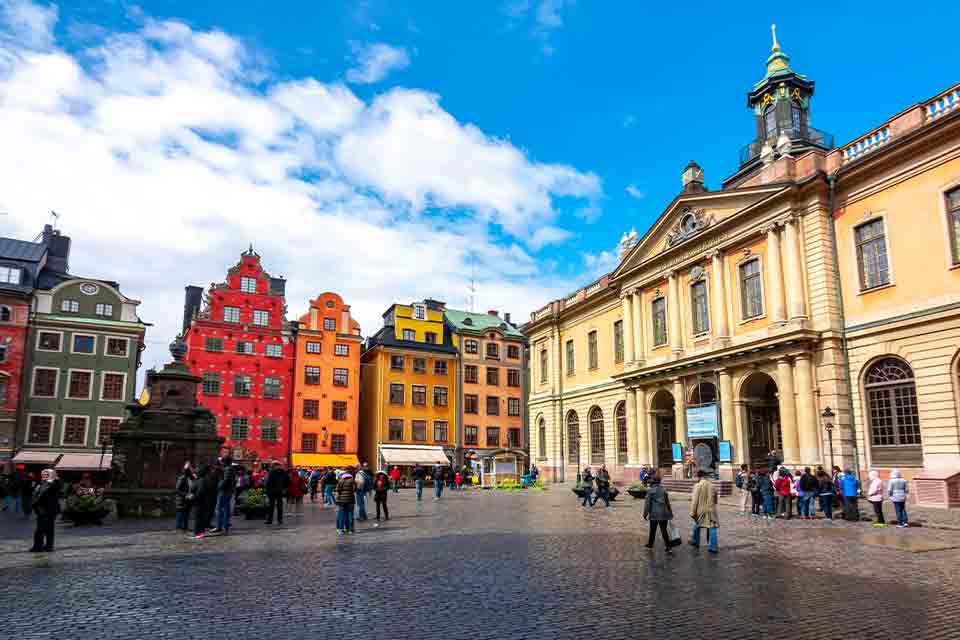 A photograph of a crisp Swedish buildings towering over a stone roadway