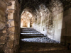 A photograph taken from inside a covered stone hallway