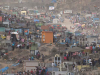 An aerial shot of a chaotic scene of hundreds of families holding simultaneously holding funerals in a massive open area