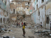 A group of boys play stickball in an urban cul-de-sac filling up with piles of rubble