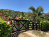 A closed gate on a dirt path, surrounded by greenery