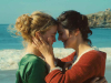 A still photograph from Portrait of a Lady on Fire that features two women standing on a beach, holding one another and pressing foreheads