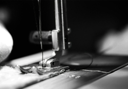 A black and white photograph showing a close up of a sewing machine at work