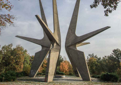 A photograph of an outdoor monument featuring three spiky geometric figures rising up out of the ground.