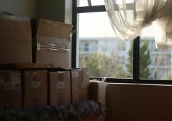 A photograph of a stack of boxes dimly lit by a window nearby