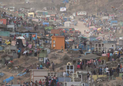 An aerial shot of a chaotic scene of hundreds of families holding simultaneously holding funerals in a massive open area