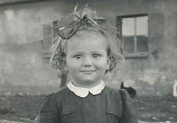 A black and white historical photograph of a young girl smiling at the camera