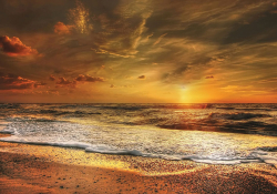 A fiery sunset pauses before dipping below the ocean's horizon